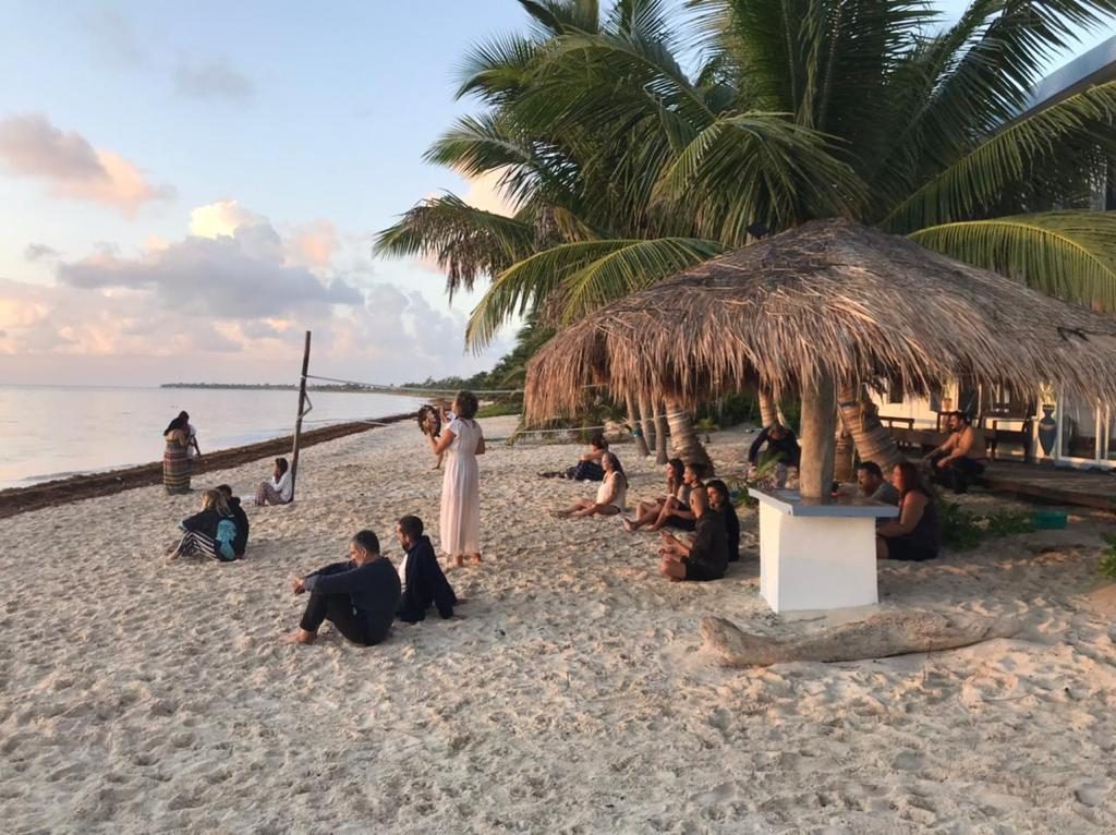 Retreat group gathered on the private beach at dusk — about 15 people around the palapa area